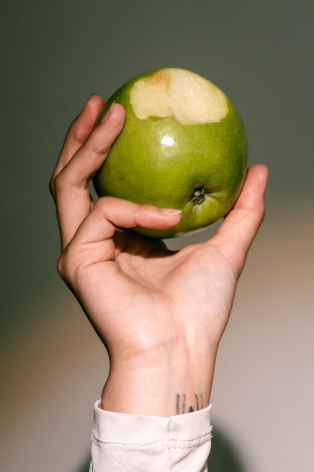 Hand holding an apple with a bite out of it